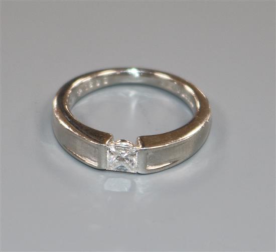 A modern platinum and channel set solitaire princess cut diamond ring, size K.